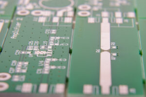Close-up of a green printed circuit board (PCB) featuring electronic components, conductive traces, and connection points.